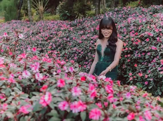 Miss Summer Summer in an emerald sequinned gown standing in a field of pink impatiens