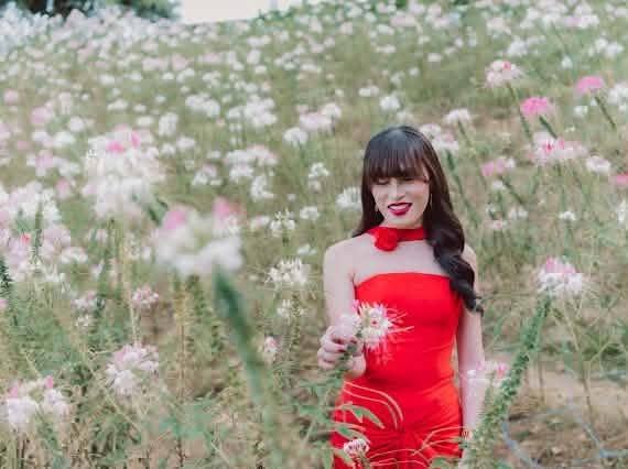 Miss Summer Summer in a red strapless gown holding a bloom in a field of white cleome flowers