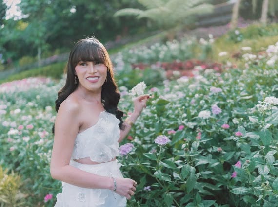 Miss Summer Summer holding a flower among the garden beds