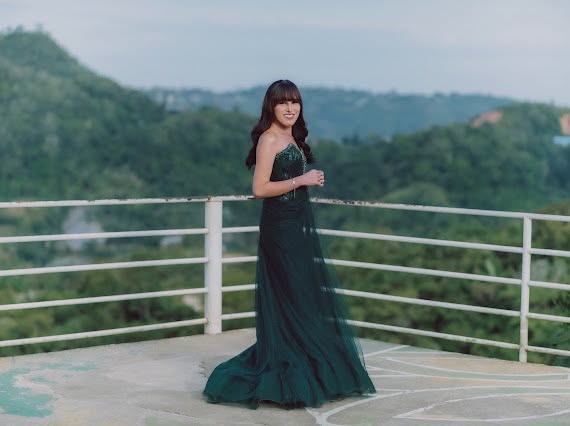 Miss Summer Summer in an emerald tulle gown at a railing above forested hills
